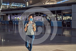 Woman in mask at empty airport at check in in coronavirus quarantine isolation, returning home, flight cancellation