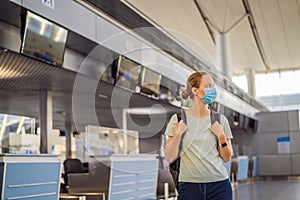 Woman in mask at empty airport at check in in coronavirus quarantine isolation, returning home, flight cancellation