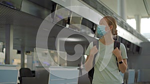 Woman in mask at empty airport at check in in coronavirus quarantine isolation, returning home, flight cancellation