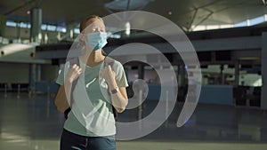 Woman in mask at empty airport at check in in coronavirus quarantine isolation, returning home, flight cancellation