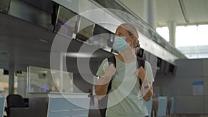 Woman in mask at empty airport at check in in coronavirus quarantine isolation, returning home, flight cancellation