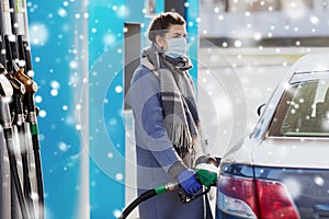 Woman in mask filling her car at gas station