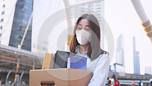 Woman with mask fired from job holding box of items