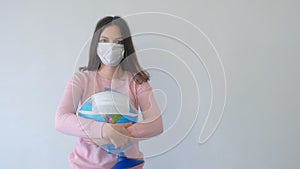 Woman in mask holding globe in mask in hands, coronavirus pandemic quarantine.