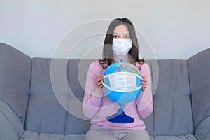 Woman in mask holding globe in mask in hands, pandemic quarantine.