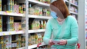 Woman in mask leaning on trolley and reading shopping list