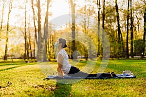 Woman with mask meditating/practicing yoga in nature alone.Social distancing and active healthy lifestyle. Mindfulness meditation.