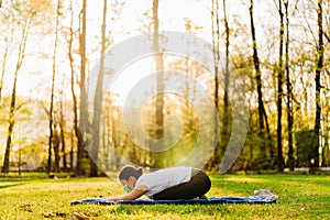 Woman with mask meditating/practicing yoga in nature alone.Social distancing and active healthy lifestyle. Mindfulness meditation.
