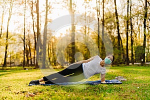 Woman with mask meditating/practicing yoga in nature alone.Social distancing and active healthy lifestyle. Mindfulness meditation.