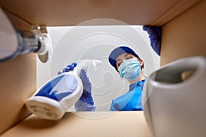 woman in mask packing cleaning supplies in box photo