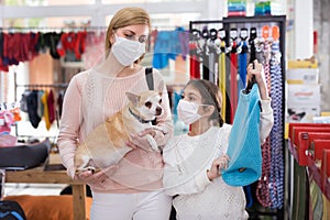 Woman in mask in pet store during shopping with her daughter with dog