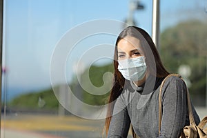 Woman with a mask preventing contagion waiting in a bus stop photo