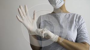 Woman with a mask putting on white sterile latex surgical gloves