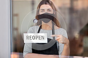 woman in mask with reopen banner on door glass