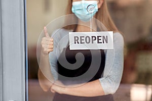 woman in mask with reopen banner showing thumbs up