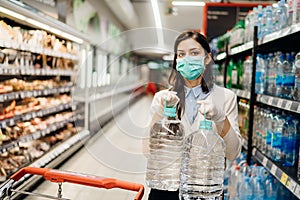 Woman with mask safely shopping for groceries amid the coronavirus pandemic in a stocked grocery store