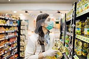 Woman with mask safely shopping for groceries amid the coronavirus pandemic in stocked grocery store.COVID-19 food buying in