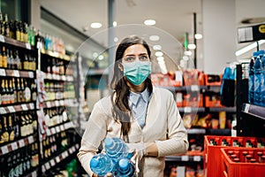 Woman with mask safely shopping for groceries amid the coronavirus pandemic in a stocked grocery store.COVID-19 food buying in