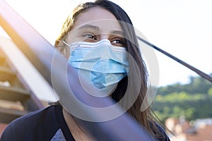 Woman with mask smiling and looking straight ahead.