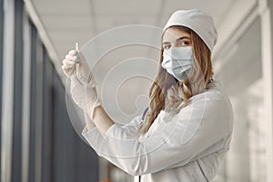 Woman in a mask and uniform holding a syringe in her hands