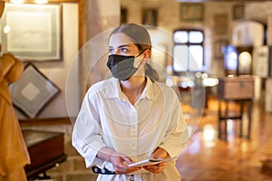 Woman in mask visiting exhibit at sculpture hall in museum