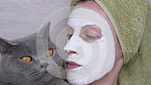 Woman in a Mask of White Clay on Face Holds a British Cat in Arms. Close-up. 4K