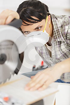 woman with mask working with circular saw photo