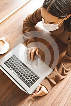 Woman in mask working at notebook