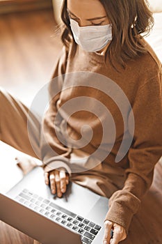 Woman in mask working at notebook