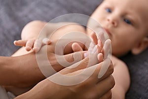 Woman massaging cute little baby on blanket