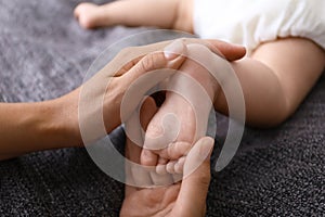 Woman massaging cute little baby on blanket