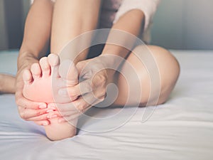 Woman massaging her painful foot, red hi-lighted on pain area