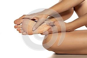 Woman massaging her painful foot on white