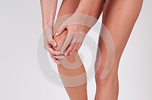 Woman massaging her painful knee, feeling pain in knee.