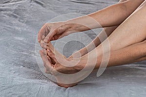 Woman massaging her toes. Revitalizing foot massage. Women& x27;s feet health care. Close-up of female hands doing