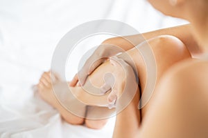 Woman massaging legs on bed