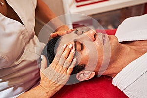 Woman is massaging man forehead with hands