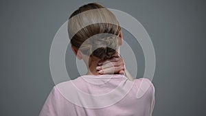 Woman massaging neck, pinched nerve, result of sedentary lifestyle, back view