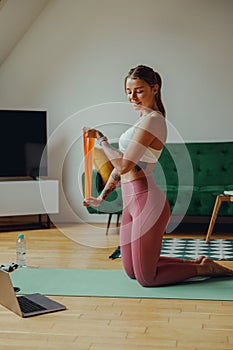 Woman on mat with resistance band for arm, thigh and waist exercises