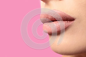 Woman with matte lipstick on pink background. Space for text