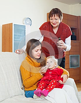 Woman with mature mother giving medicament to baby