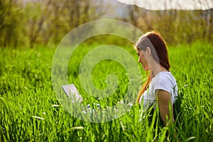 woman on the meadow relaxing and using a laptop