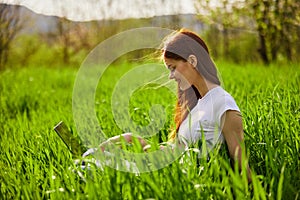 woman on the meadow relaxing and using a laptop