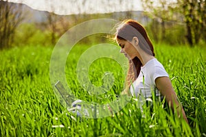 woman on the meadow relaxing and using a laptop