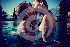 Woman and mean in honeymoon kissing in pool