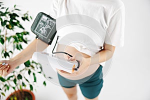 A woman measures blood pressure with an electronic pressure gauge, headache during pregnancy, poor health. selective