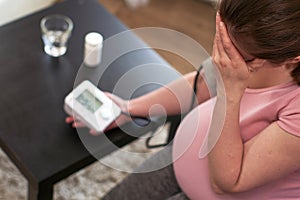 A woman measures blood pressure with an electronic pressure gauge, headache during pregnancy, poor health.selective focus on the