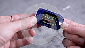 Woman Measures Pulse and Oxygen Saturation Using a Pulse Oximeter at Home