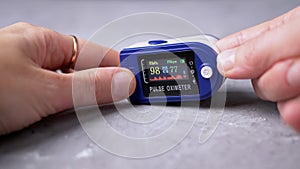 Woman Measures Pulse and Oxygen Saturation Using a Pulse Oximeter at Home