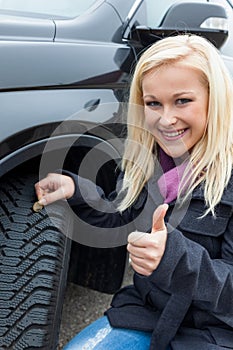 Woman measures tire tread of a car tire